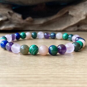 A semi precious beaded gemstone bracelet made with flexible strong stretch cord with crystals to help with all aspects of childbirth and post natal. It is made with 6mm moonstone, rose quartz, moss agate, malachite, amethyst, chrysocolla crystals.