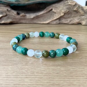 May include: A green and white beaded bracelet with various shades of green and white beads. The bracelet is made of natural stones.