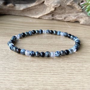 May include: A black, white, and gray beaded bracelet with a stretchy band.