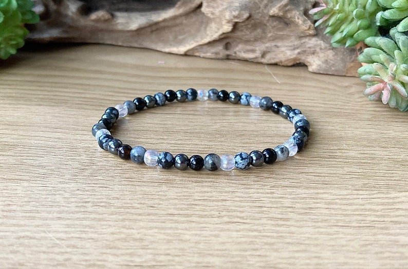 May include: A black, white, and gray beaded bracelet with a stretchy band.