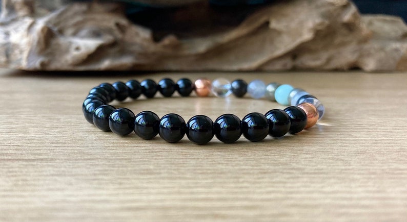May include: A black beaded bracelet with a variety of other colored beads, including copper, clear, and green.