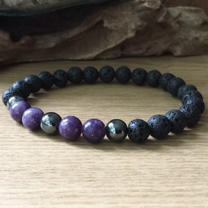 May include: A beaded bracelet with black lava rock beads, purple amethyst beads, and silver hematite beads.
