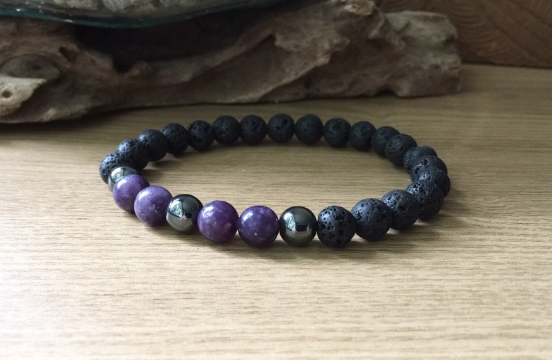 May include: A beaded bracelet with black lava rock beads, purple amethyst beads, and silver hematite beads.