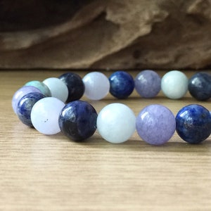 May include: A bracelet made of blue, light blue, and lavender coloured round beads.