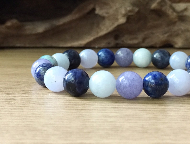 May include: A bracelet made of blue, light blue, and lavender coloured round beads.