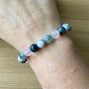 Puede incluir: Un brazalete hecho de cuentas de piedras preciosas verdes, blancas y rosas. El brazalete est&aacute; en la mu&ntilde;eca de una persona.