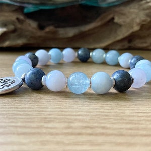 May include: A blue and white beaded bracelet with a silver charm featuring a lotus flower design.