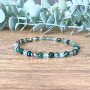 May include: A green and white beaded bracelet with gold accents. The bracelet is made of natural stones and is a beautiful and unique piece of jewellery.