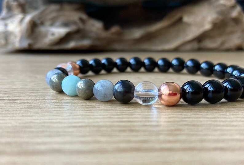 May include: A black beaded bracelet with a variety of gemstone beads, including clear quartz, black onyx, pyrite, and green aventurine.