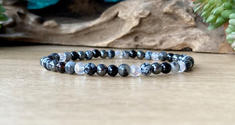 May include: A black, gray, and white beaded bracelet with a mix of round and oval beads.