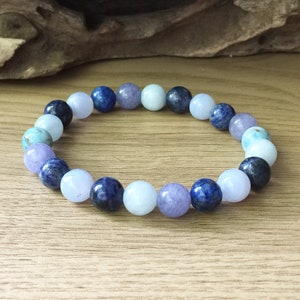 May include: A bracelet made with round beads of blue, purple and light blue gemstones.