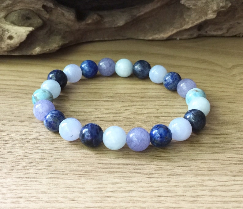 May include: A bracelet made with round beads of blue, purple and light blue gemstones.