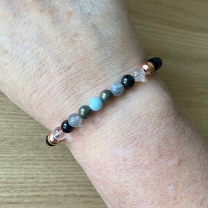 May include: A bracelet with black, gray, and blue beads, interspersed with clear and rose gold beads.