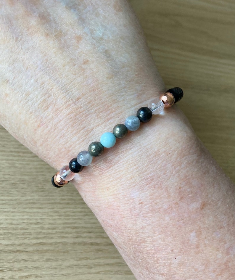 May include: A bracelet with black, gray, and blue beads, interspersed with clear and rose gold beads.