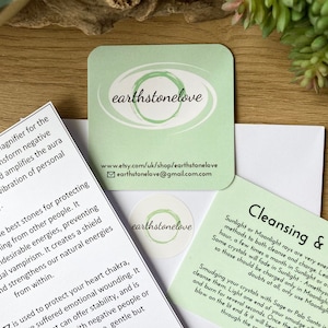 May include: Green card with the text "earthstonelove" and a website address. The card also includes instructions for cleansing crystals with sunlight or moonlight.