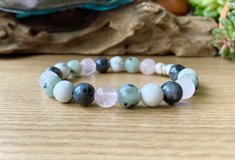 Puede incluir: Un brazalete hecho de cuentas verdes, blancas y rosas. Las cuentas son redondas y tienen un acabado liso. El brazalete est&aacute; encordado en un cord&oacute;n plateado.