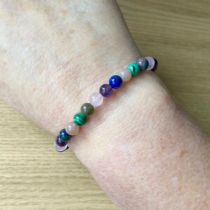 Peut inclure: Un bracelet en perles multicolores avec des perles vertes, roses, violettes et bleues.