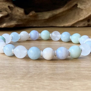 May include: A bracelet made of light blue, white, and green gemstone beads with silver spacers.