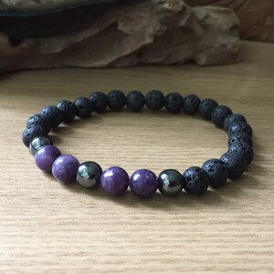 May include: A black lava rock and purple gemstone beaded bracelet.