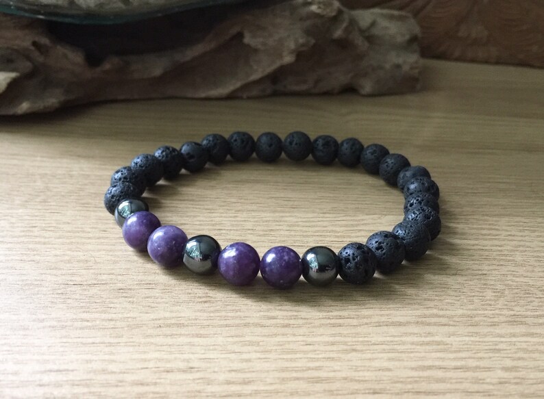 May include: A black lava rock and purple gemstone beaded bracelet.