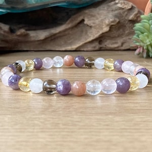 May include: A bracelet made of various semi-precious stones, including amethyst, clear quartz, citrine, and carnelian. The bracelet is made of round beads and is strung on elastic.