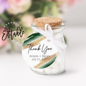 Puede incluir: Una etiqueta redonda blanca de agradecimiento con acentos de acuarela verde y dorado. La etiqueta dice "Gracias" con los nombres "Kristin + Derek" y la fecha "21 de julio de 2021".