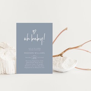 May include: A light blue baby shower invitation with white text that reads "oh baby!" and includes details for a baby shower honoring Madison Williams on August 20th at 12 o'clock at Morning Magnolias Cafe. The invitation also includes the address and RSVP information.
