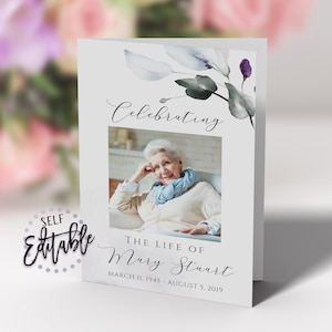 May include: A white card with a watercolor floral design in shades of blue and purple. The card has a photo of a woman in the center and the text "Celebrating The Life of Mary Stuart March 11, 1945 - August 5, 2019".
