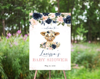 May include: Welcome to Larissa's Baby Shower sign with a cute cartoon calf wearing a floral crown. The sign is decorated with pink and blue flowers and has a white background with pink and white confetti.
