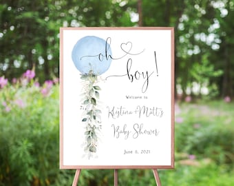 Puede incluir: Un cartel de bienvenida para una fiesta de bienvenida al bebé azul y blanco con el texto "Oh boy!" y un globo azul con un corazón. El cartel también incluye el texto "Bienvenido a Kristina + Matt's Baby Shower June 8, 2021".