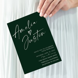 Puede incluir: Una tarjeta de invitaci&oacute;n de boda verde oscuro con caligraf&iacute;a blanca que dice "Amelia & Justin" con un peque&ntilde;o s&iacute;mbolo de coraz&oacute;n entre los nombres. La invitaci&oacute;n detalla la fecha, la hora, el lugar y la informaci&oacute;n de la recepci&oacute;n de la boda.