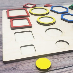 May include: Wooden board with cutouts of different shapes, including circles, squares, hexagons, and a trapezoid.  The shapes are painted in various colors, including red, blue, green, and yellow.