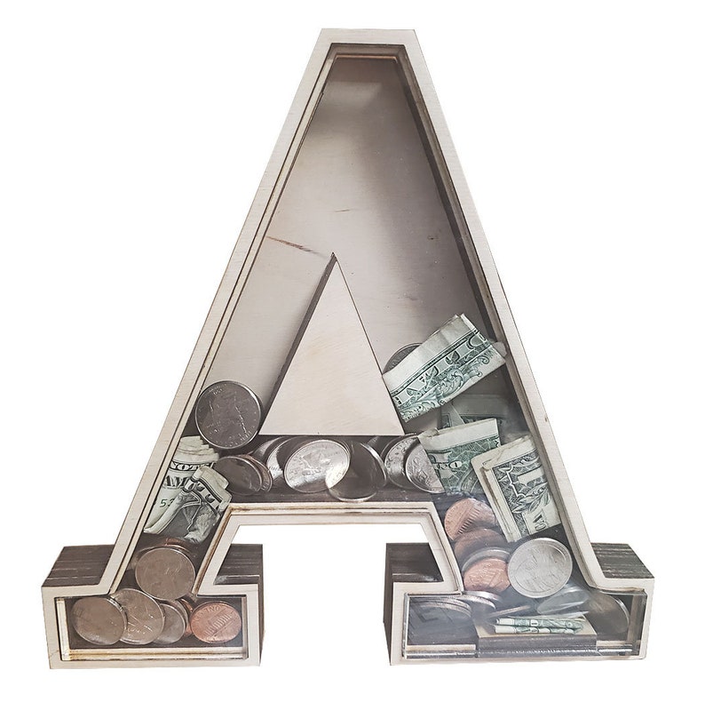 May include: Wooden letter A piggy bank with a clear plastic front. The bank is filled with coins and dollar bills.
