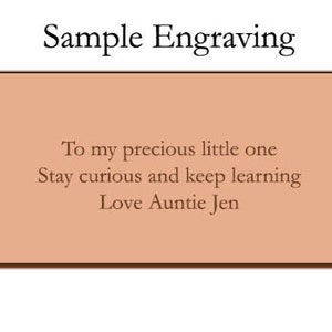 May include: A sample engraving on a light brown background with the text "To my precious little one Stay curious and keep learning Love Auntie Jen".