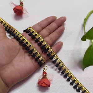 Cinta de encaje de tela con diseño de flecos y borlas de color negro y dorado indio cortada a medida utilizada en diferentes diseños en múltiples artefactos.