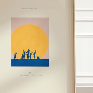 May include: A framed print with a minimalist design featuring a yellow sun and blue silhouettes of people. The text "LES MOULINS A VENT" and "LA VRAIE FAMILLE SONT AMIS" is printed below the image.