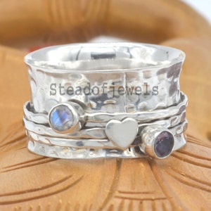 May include: A silver spinning ring with a hammered finish. The ring has three charms: a heart, a moonstone, and an amethyst.