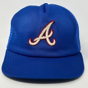 Puede incluir: Gorra de béisbol azul con visera curva y parte trasera de malla. La gorra presenta una letra "A" bordada en blanco y rojo en la parte delantera. Un sombrero de estilo clásico, adecuado para deportes o uso diario.