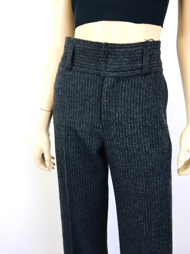 Puede incluir: Pantal&oacute;n gris de rayas finas con cintura alta y cintur&oacute;n ancho.