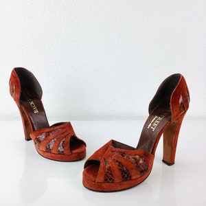 May include: A pair of brown suede platform heels with a snakeskin pattern. The heels are about 4 inches tall and have a peep toe design. The shoes are labeled "Feet First" on the inside.