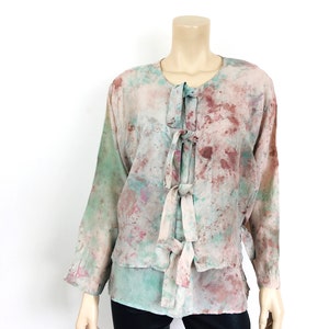 May include: A long-sleeved, tie-front blouse with a tie-dye pattern in shades of pink, green, and brown. The blouse is made of a lightweight fabric and has a relaxed fit.