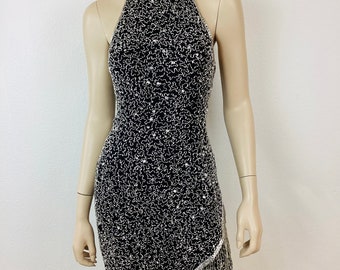 May include: A black halter dress with silver sequins and fringe. The dress has a fitted bodice and a flowing skirt.