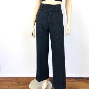 Puede incluir: Pantal&oacute;n de pierna ancha de cintura alta con un patr&oacute;n de rayas finas en gris oscuro y negro. El pantal&oacute;n tiene un dobladillo con vuelta y una cintura con trabillas.