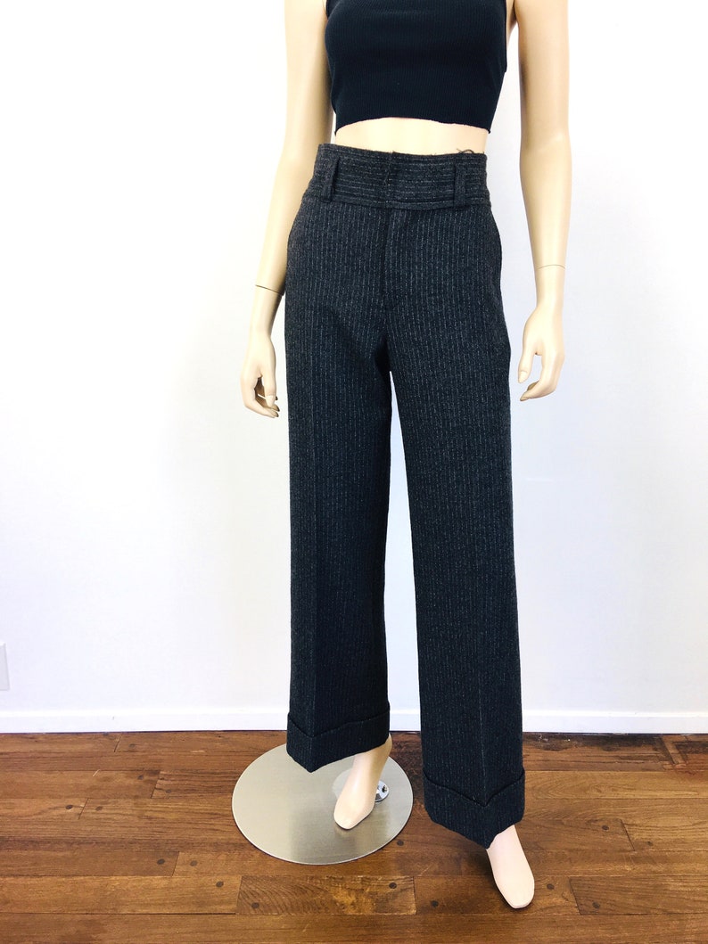 Puede incluir: Pantal&oacute;n de pierna ancha de cintura alta con un patr&oacute;n de rayas finas en gris oscuro y negro. El pantal&oacute;n tiene un dobladillo con vuelta y una cintura con trabillas.