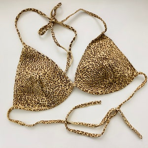 May include: A brown and tan leopard print bikini top with adjustable straps.
