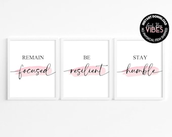 May include: Three white framed prints with pink watercolour accents and black calligraphy. The prints read "Remain focused", "Be resilient", and "Stay humble".