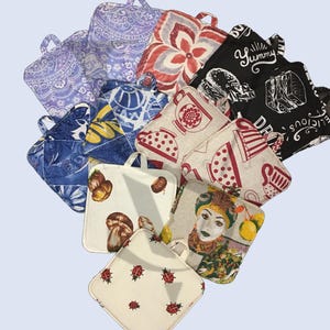 Könnte beinhalten: Eine Sammlung von zehn bunten und gemusterten Topflappen. Die Topflappen sind aus Stoff und haben einen Schlaufe. Die Designs beinhalten Blumen, Teetassen, Marienkäfer und Essen.