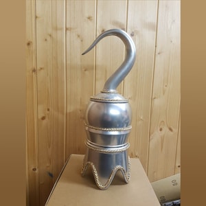 以下が含まれることがあります： 湾曲した刃を持つ銀色の海賊フック小道具。フックは、金色のロープのアクセントが付いた装飾的なベースに取り付けられています。ベースは、一連の積み重ねられたセクションを持つ丸みを帯びた形状をしています。