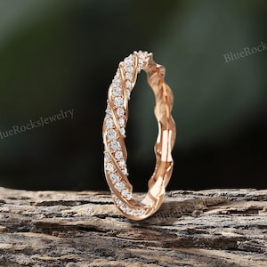 Peut inclure: Une bague en or rose avec un design torsadé et une rangée de petits diamants sertis dans la bande.