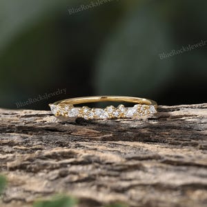 May include: A delicate gold band ring with a row of small, clear marquise-shaped diamonds set in a pave setting.